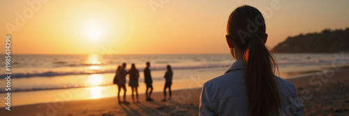 Sunset beach scene with person observing friends enjoying time by ocean waves and setting sun, creating lasting memories. Relaxing beach atmosphere fosters connection among friends in tranquil moment.