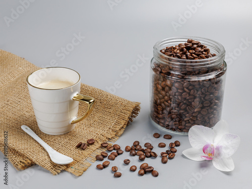 Cup of coffee and a glass can with roasted coffee beans.