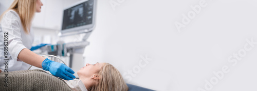 An endocrinologist examines a patient's thyroid gland using an ultrasound machine. Ultrasound machine banner copy space