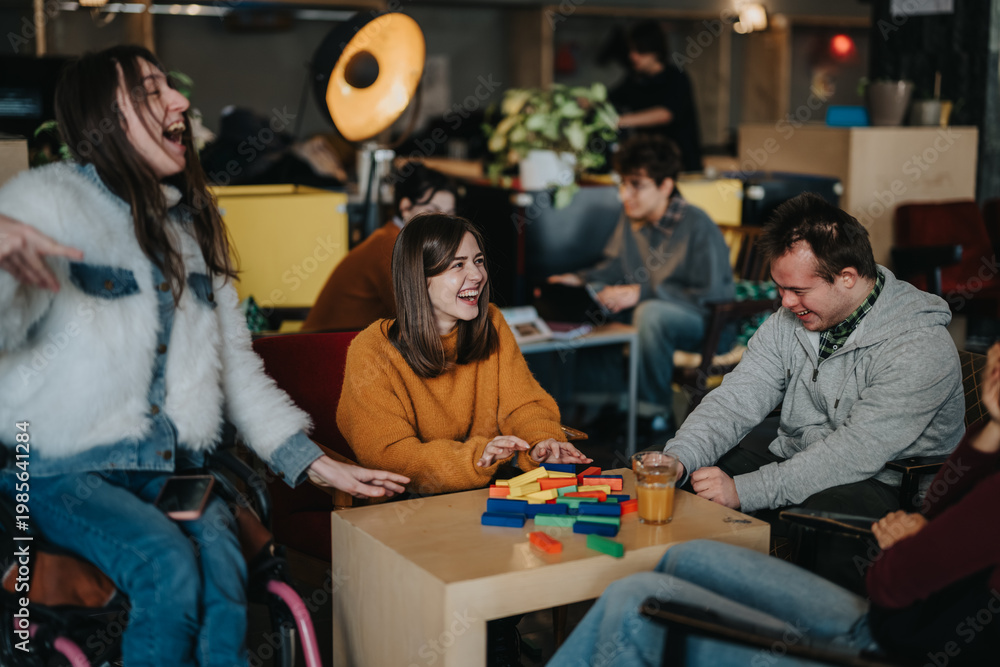 Fototapeta premium A group of students, including wheelchair users and people with disabilities, laugh while playing a colorful block game at a table.