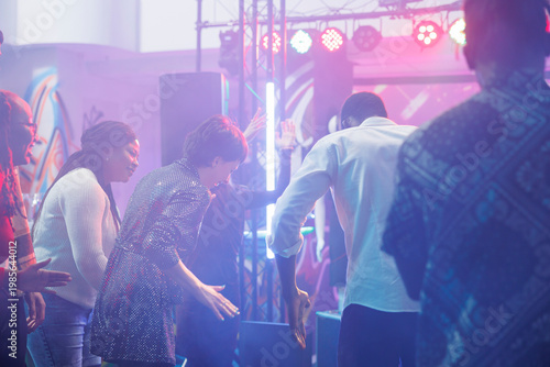 Foto Cheerful clubbers laughing while improvising dance battle at discotheque in nightclub