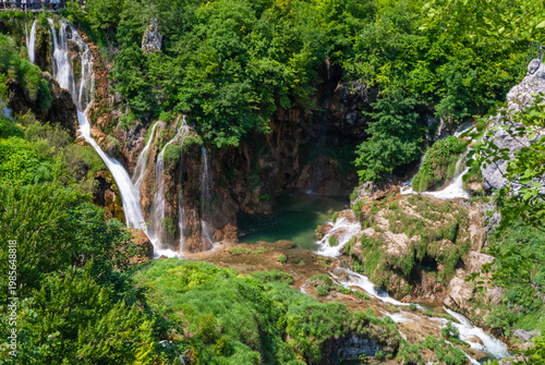 Plitvice Lakes is National Park in Croatia. Stunning series of waterfalls cascading down lush green cliffs into tranquil turquoise pool, surrounded by dense forest and vibrant vegetation.