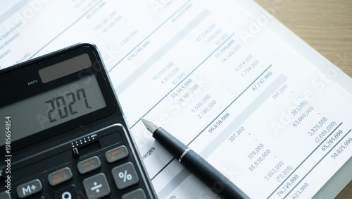 Фотография Calculator showing 2027 on financial report with pen, annual budget planning, business forecast and finance management concept