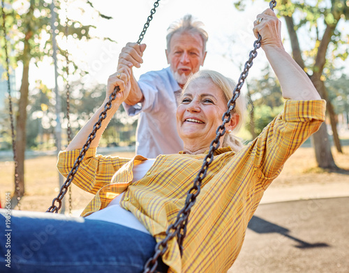 Bilde på lerret Happy active senior woman having fun on a swing in park outdoors