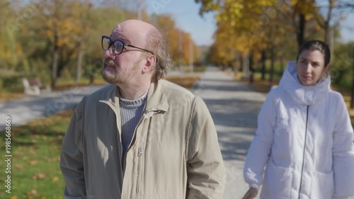 Autumn park walk with elderly man and compassionate caregiver