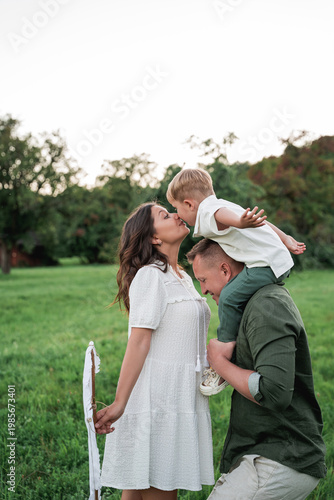 Happy young family with little son playing with kite in field. Healthy childhood.