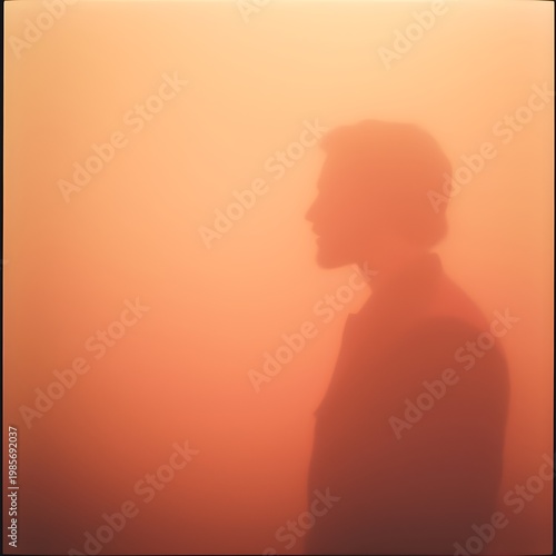 Soft silhouette of a man in profile behind a warm orange gradient, creating a minimal, dreamy and atmospheric portrait with gentle light and blurred edges.