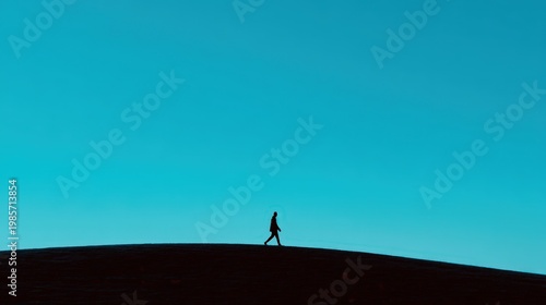 Solitary Figure Walking Silhouetted Against a Bright Blue Sky