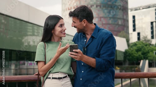 Video of lovely couple talking and laughing while looking together at smartphone in the city