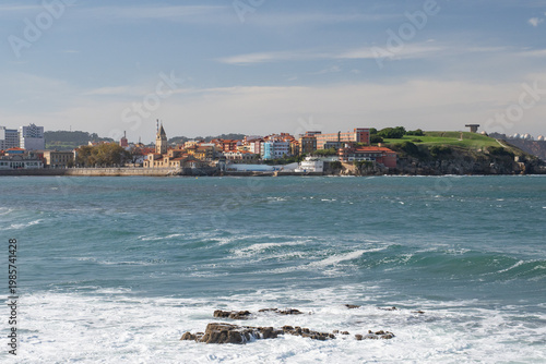 San Pedro Church and San Lorenzo beach with surfers at sunset in Gijon, Asturias, Spain.