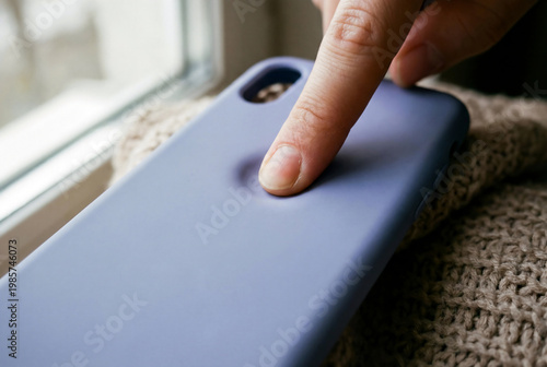 Close-up of finger pressing on soft silicone purple smartphone case showing flexible material texture and liquid silicone quality.