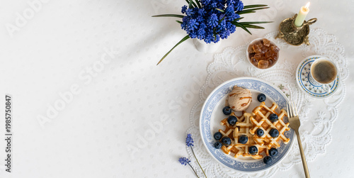 Plate of waffles with blueberries and ice cream banner, arranged on a table with coffee and flowers, perfect for breakfast and brunch promotions, restaurant menus, food photography, copy space 