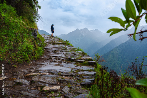 A lone hiker walks along a stone path in the mountains of Madhyamaheshwar temple, Uttarakhand, India
