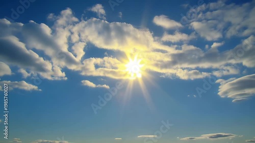 Sun shining through white clouds in the blue sky creating a beautiful natural landscape background
