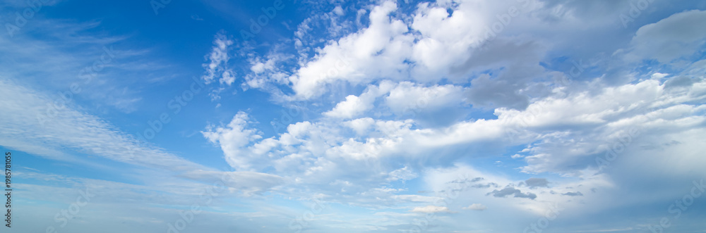Fototapeta premium Vibrant blue sky panorama with fluffy white clouds and bright sunlight.