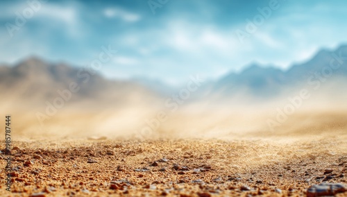 Arid desert floor detailed, with wind-blown sand haze, blurry distant mountains, blue sky
