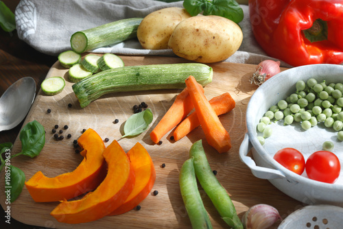 Selection of vibrant farm vegetables and vintage metal utensils on rustic kitchen board. Close-up composition displays fresh seasonal ingredients ready for traditional homemade soup capturing