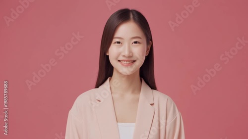 Young Asian Woman Smiles Happily Looking at Camera Against Pink Background