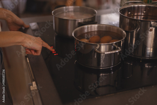 Fényképezés Woman hand pressing sensor button on modern electric induction hob to boil eggs