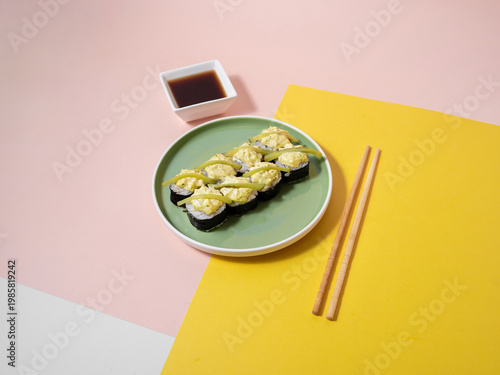 Bright green plate features creamy avocado rolls with soy sauce