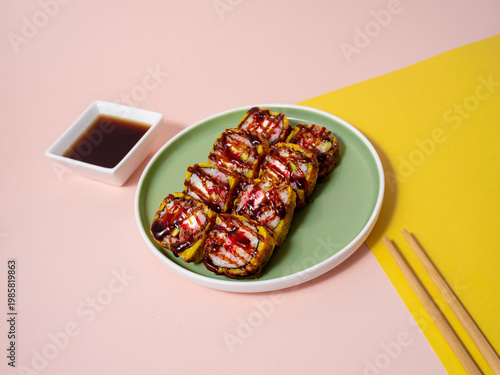 Photo capturing gourmet sushi on vibrant plate accompanied by sauces