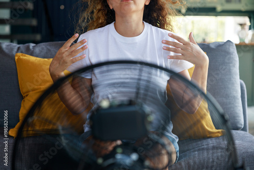 Foto Woman trying to cool herself with electric fan during heatwave at home