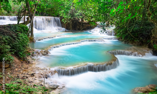 Scenic turquoise cascades of Kuang Si waterfall near Luang Prabang, Laos. Tropical jungle landscape with limestone pools and lush rainforest vegetation, a famous natural attraction in Southeast Asia.