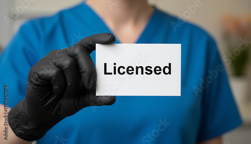 Medical professional holds Licensed card, wearing blue scrubs and black gloves. Healthcare professional shows authorization for service, confirming medical practice.  Healthcare and Professional Servi