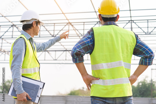 Builder team, foreman asian young engineer, architect man, male are discussing construction drawing on blueprint follow project to build an industrial plan at outdoor site. Engineering worker people.