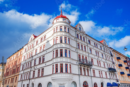 Photography Beautiful white neoclassical apartment building featuring a rounded corner tower with a red roof