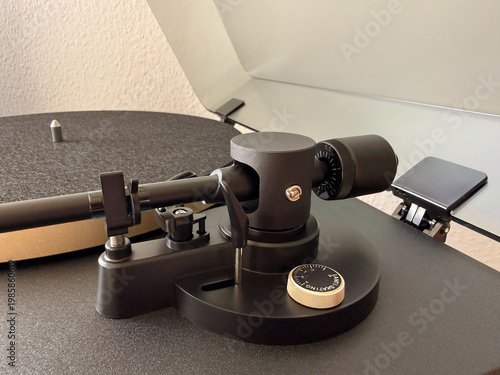 Close-up of a modern turntable tonearm assembly featuring the counterweight and anti-skating adjustment dial. High-quality analog audio equipment showing precise mechanical details for audiophiles.