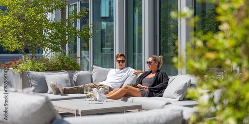 A relaxed couple relaxes while sitting on an outdoor sofa on a terrace on a sunny day