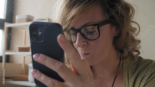 Woman with glasses smiling during a video call on her phone at home