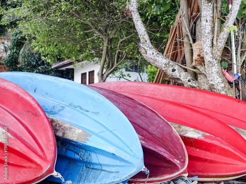 Bright red and blue canoes stacked upside down on a tropical shore. A vibrant image perfect for travel, outdoor recreation, and summer themes.