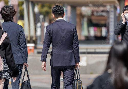 Принти на полотні Sales reps in dark suits carrying business bags walk along bustling plaza as pedestrians and other professionals pass nearby, reflecting the daily rhythm of the corporate workforce