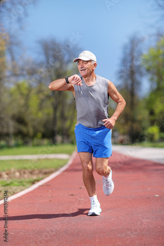 Elderly man running on a track and checking his smartwatch