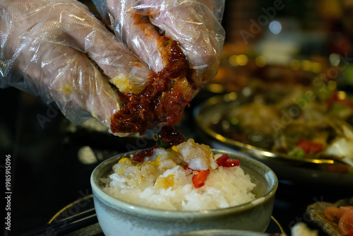 Gloved hands preparing spicy dish