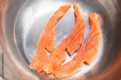 Fresh salmon fillets arranged in stainless steel bowl for culinary preparation