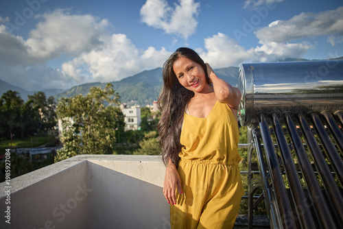 Woman in yellow dress standing on courtyard hand brushing hair wind-blown effect
