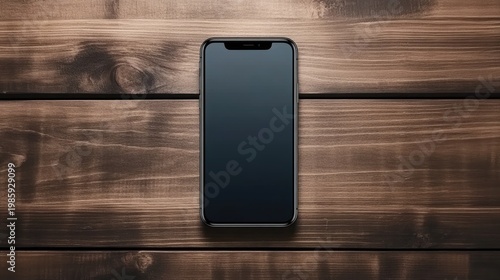 A black screen smartphone rests on a wooden table, illuminated by soft light, enhancing its modern design in a dark ambiance
