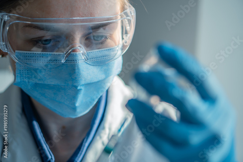 Bild auf Leinwand A laboratory scientist in safety gear inspects a sample vial with concentration, highlighting modern research practices