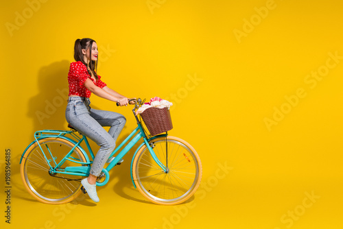 Obraz na płótnie Young woman rides a retro turquoise bike with a basket on a bright yellow backgr