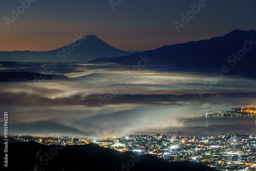 Canvas Print Breathtaking night view of a sea of clouds illuminated by city lights with Mount Fuji at dawn, Suwa Lake, Nagano, Japan