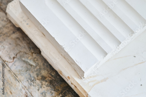 Close up of white moulded plaster decorative trim with stepped profile on wooden surface for interior design and construction detail. Manufacture and construction of moulds 