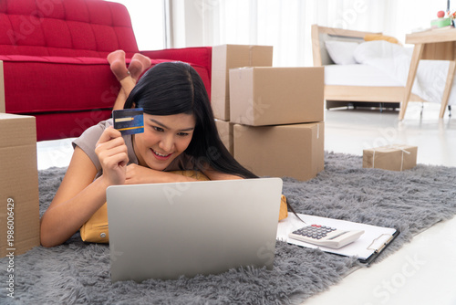 Digital Dreams: A woman lounges comfortably at home, captivated by the world of online shopping, credit card in hand. Exploring digital realms through her laptop.