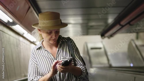 Young woman using smartphone on escalator, urban commute and modern lifestyle concept