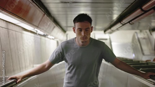 Young man riding escalator underground with confident look, urban commute and modern lifestyle concept
