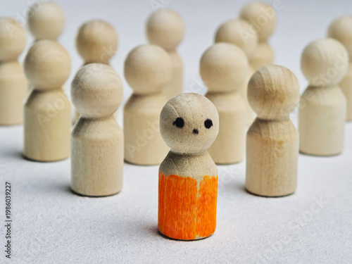 Wooden peg figures show different roles in teamwork and leadership while symbols stand out against neutral background