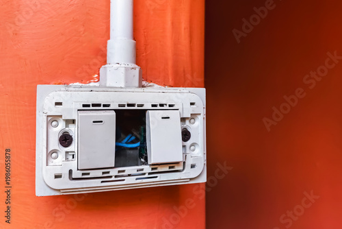 Dangerous broken electricity outlet socket and light switch on wall hole. Old damaged and broken electric switches and socket without cover on concrete wall. Power outlet sockets without the covering.