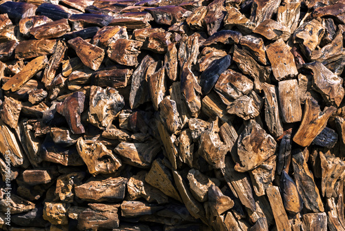 Weathered wooden planks texture background. Stacked reclaimed scrap wood pieces with charred edges. Pile of irregular aged timber blocks for carpentry and woodwork. pattern of old burnt wood stacked.